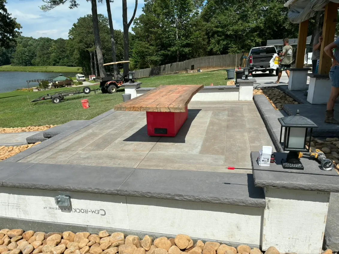 Lakeside outdoor living space with a concrete patio, bar counter and seating walls under construction by OTM Concrete