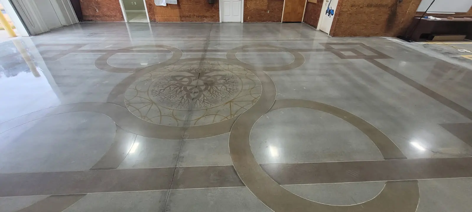 High-gloss polished concrete floor with a custom stained medallion and circular inlay design by OTM Concrete