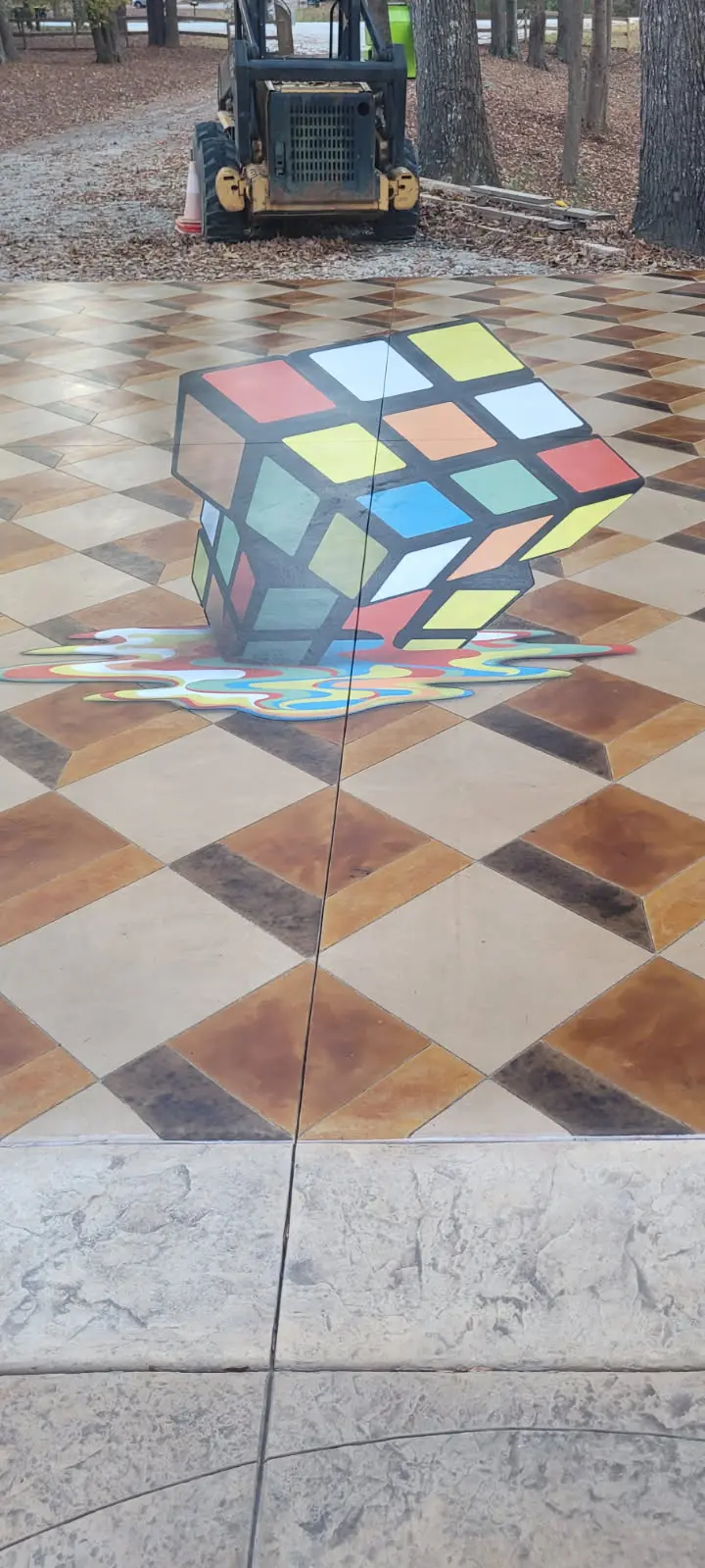 Custom hand-painted Rubik's cube graphic on a stained concrete driveway overlay by OTM Concrete