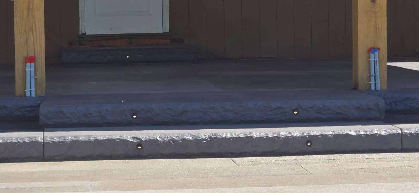 Stamped concrete steps with charcoal accent bands and recessed step lighting by OTM Concrete